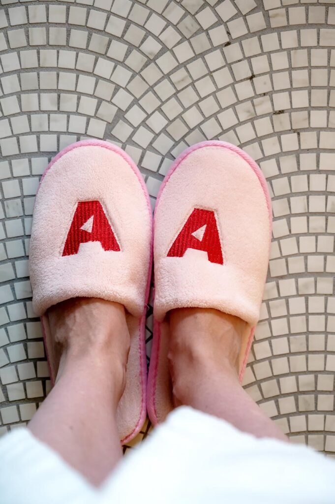 Amerikalinjen pink slippers with the letter A on the bathroom floor.