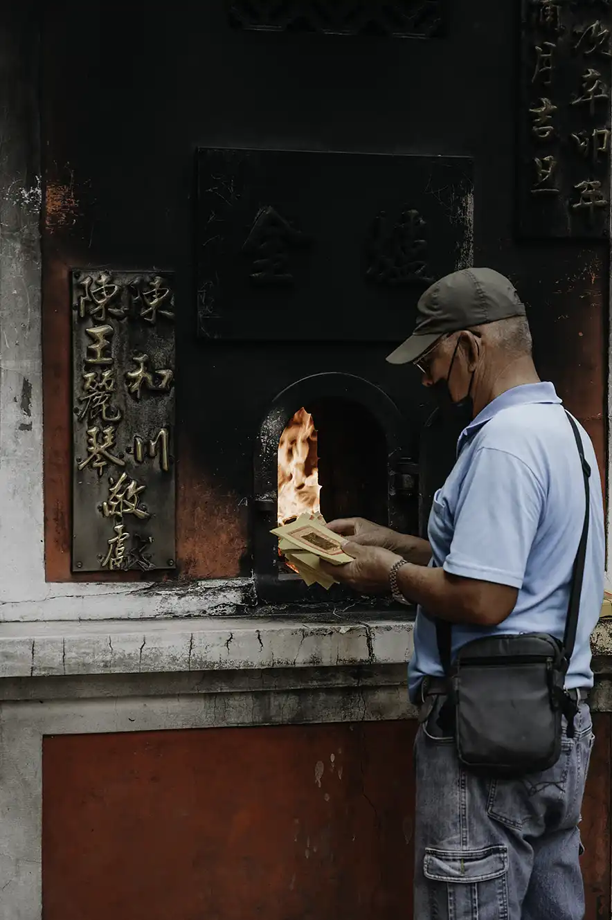 Een man gooit joss papier in het vuur bij de Grand Mazu Tempel in Tainan, Taiwan