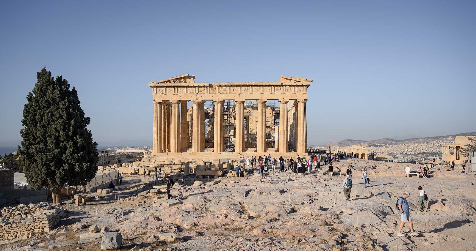 Tourists standing in front of the Parthenon on the Acropolis in Athens in the morning. View of the city of Athens.