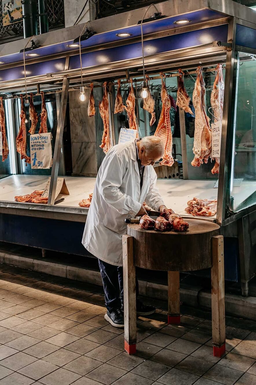 Slager hakt vlees in de Varvakeios markthallen in Athene