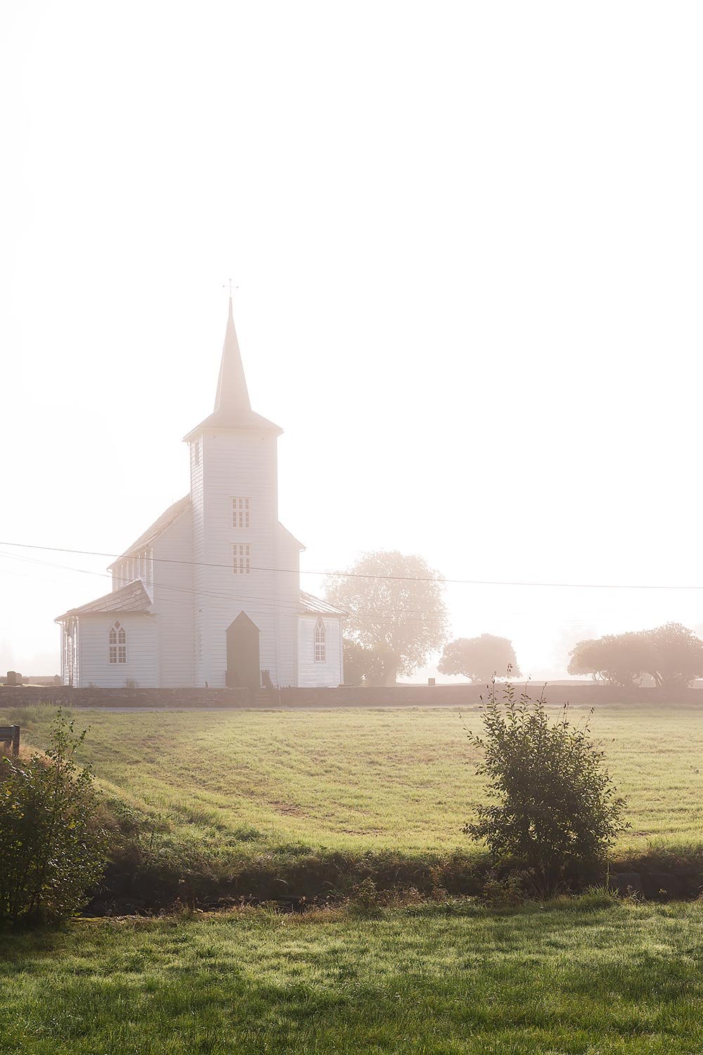 White wooden church surrounded by fog on the way from Bergen to Hardangerfjord in Norway
