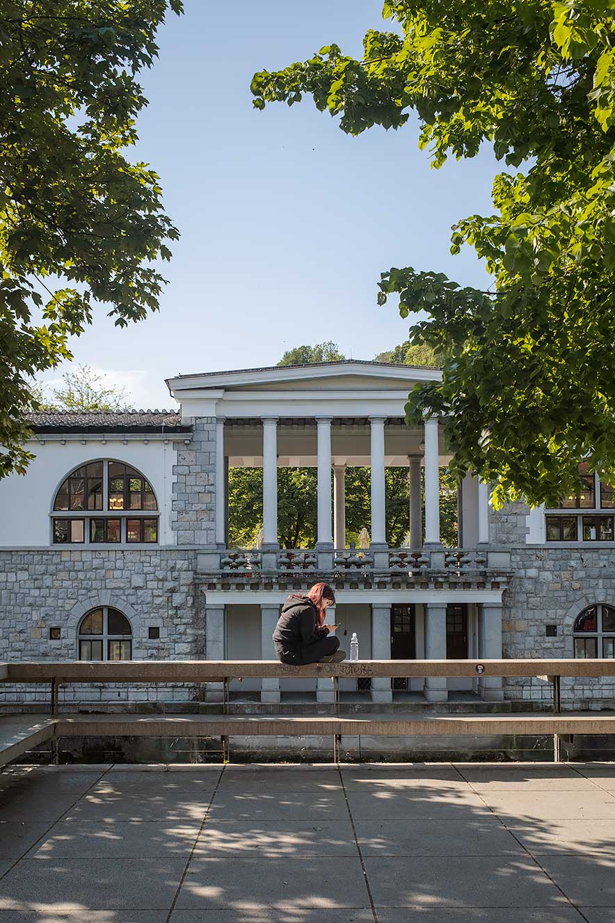Girl sitting by the Ljubljanica River with the Plecnik arcades